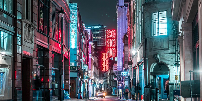 A close-up of the iconic Soho sign amidst historic buildings in London.